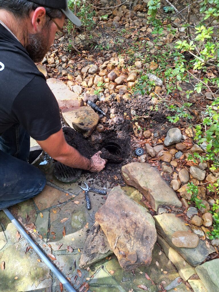 man cleaning clogged yard drainage