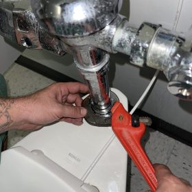 man fixing toilet pipe